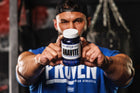 Close-up of a person holding a bottle of Anavite multivitamin by Gaspari Nutrition, showcasing the product in a gym setting.