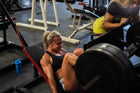 A woman performing leg press exercises in a gym, showcasing her strength and focus, with weights being loaded on the machine.