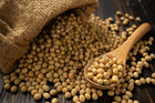 A burlap sack spilling out soybean seeds onto a wooden surface, showcasing the natural source of soy lecithin, an ingredient beneficial for health.