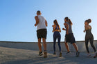 Group of diverse individuals engaging in power walking outdoors, showcasing an active lifestyle under a clear blue sky.